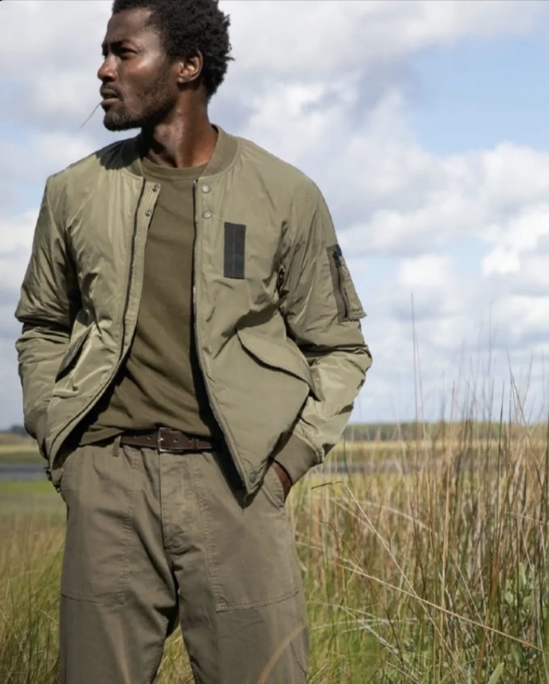 Man in olive bomber jacket in field
