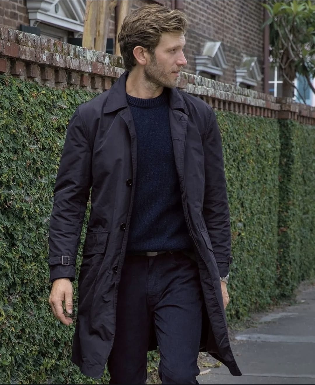 Man in navy trench coat walking street